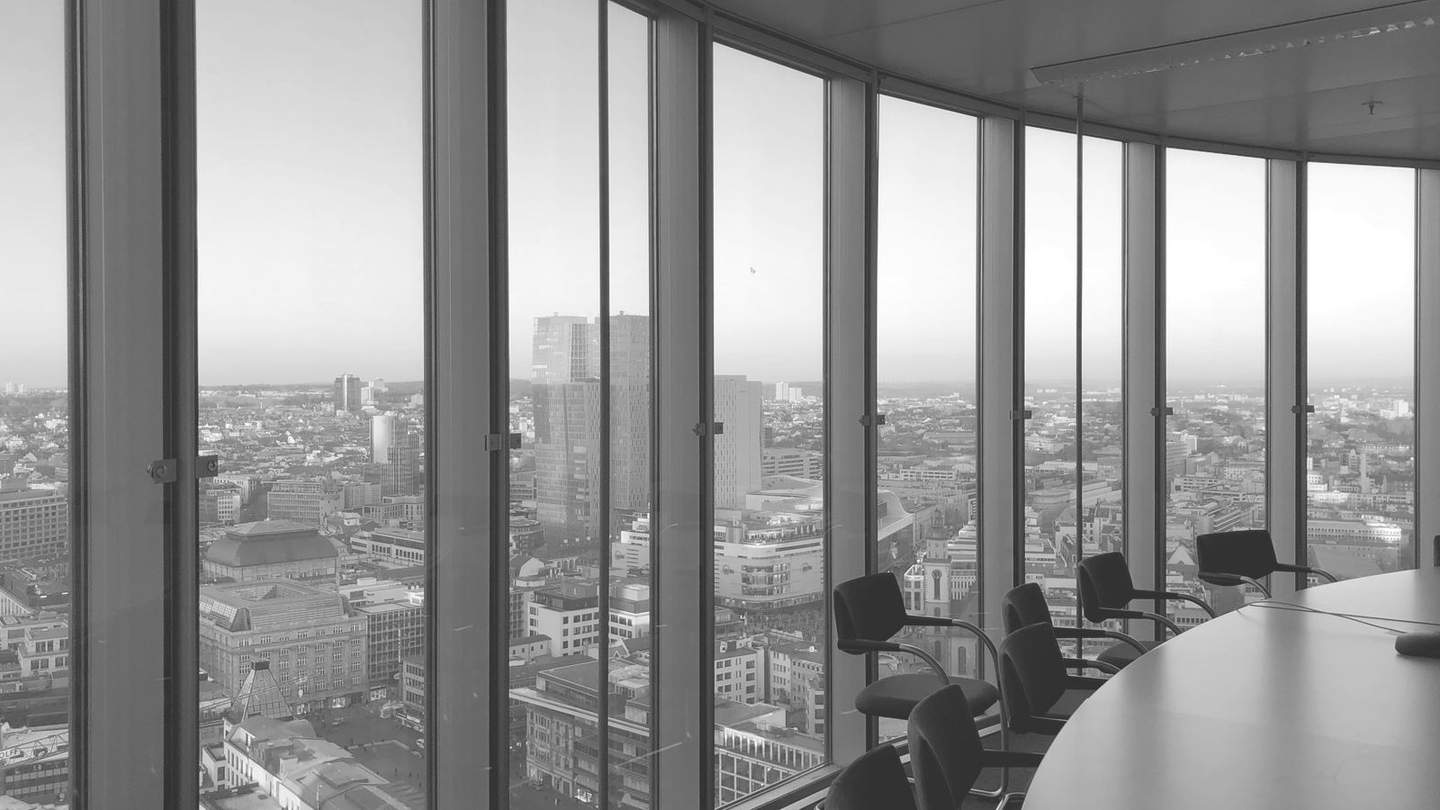 View from inside an office boardroom overlooking a city skyline, in black and white