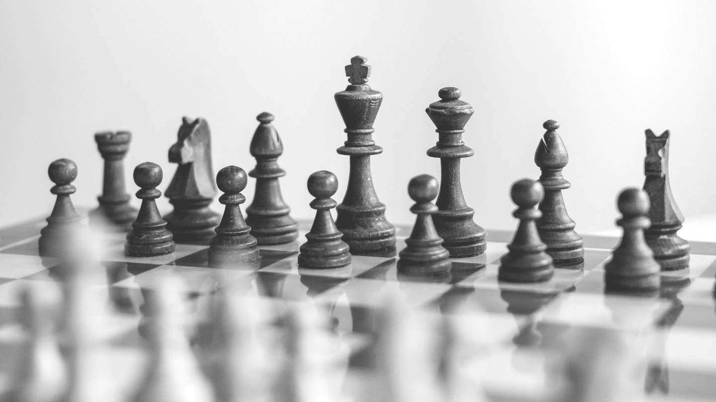 Close-up of a wooden chess set mid-game, in black and white