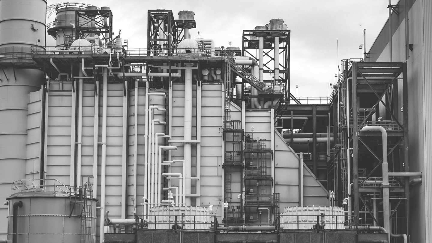Detail of industrial piping and machinery at a processing facility, in black and white